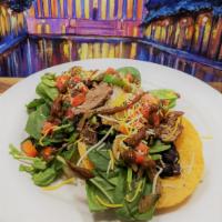 Grilled Steak Tostada Salad · Two Crispy Corn Tortillas topped with Fresh Baby Spinach, Slices of Grilled Steak, Tomatoes,...