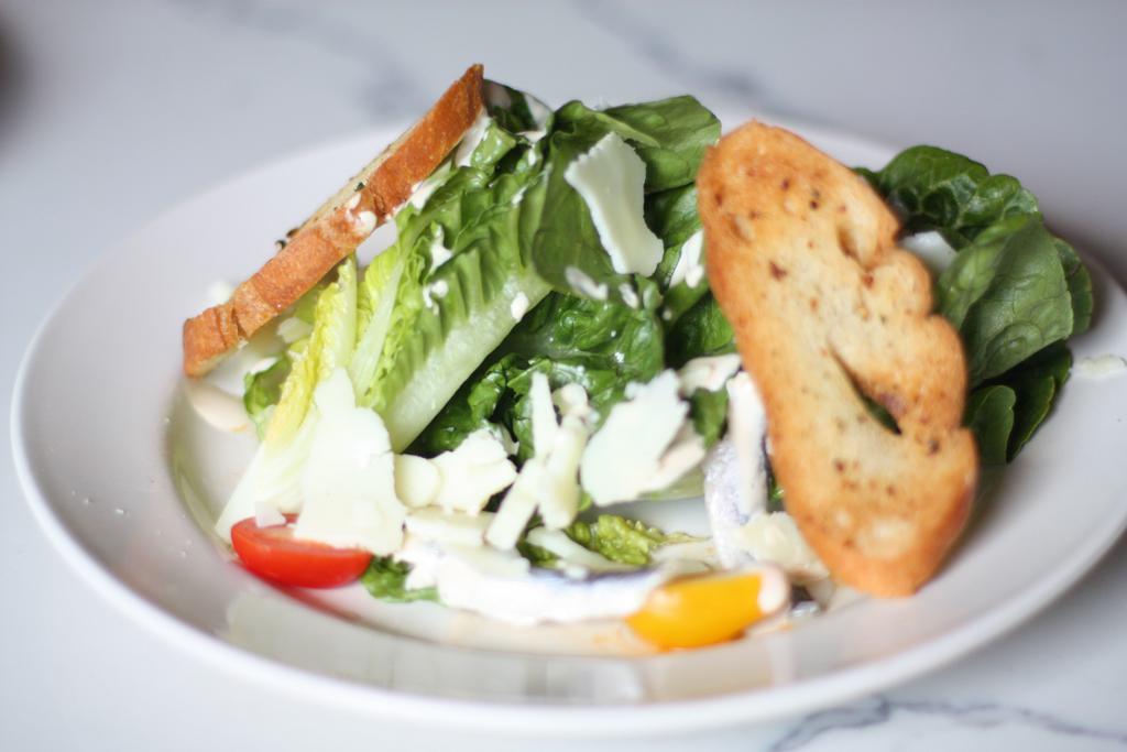 Caesar Salad · Baby romaine, shaved Parmesan, croutons  and lemon garlic dressing.