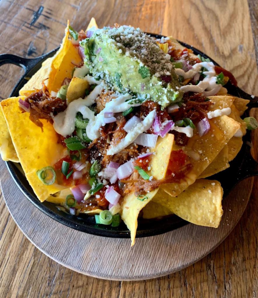 BBQ'd Pulled Pork Nachos · Ranchero beans, nacho and colby jack cheese, mexicna crema, cilantro, scallions, red onions and avocado mash.
