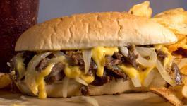 Philly Cheesesteak · Sizzling steak, yellow American cheese and sauteed onions sandwiched on a sub roll.