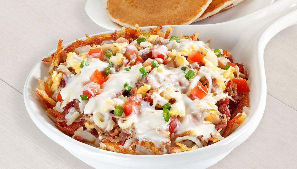 Carnitas Queso Skillet · Two scrambled eggs, pulled pork, bacon, sausage, tomatoes, onions, on a bed of seasoned hash browns, topped with jack cheese, white queso, green onions.			