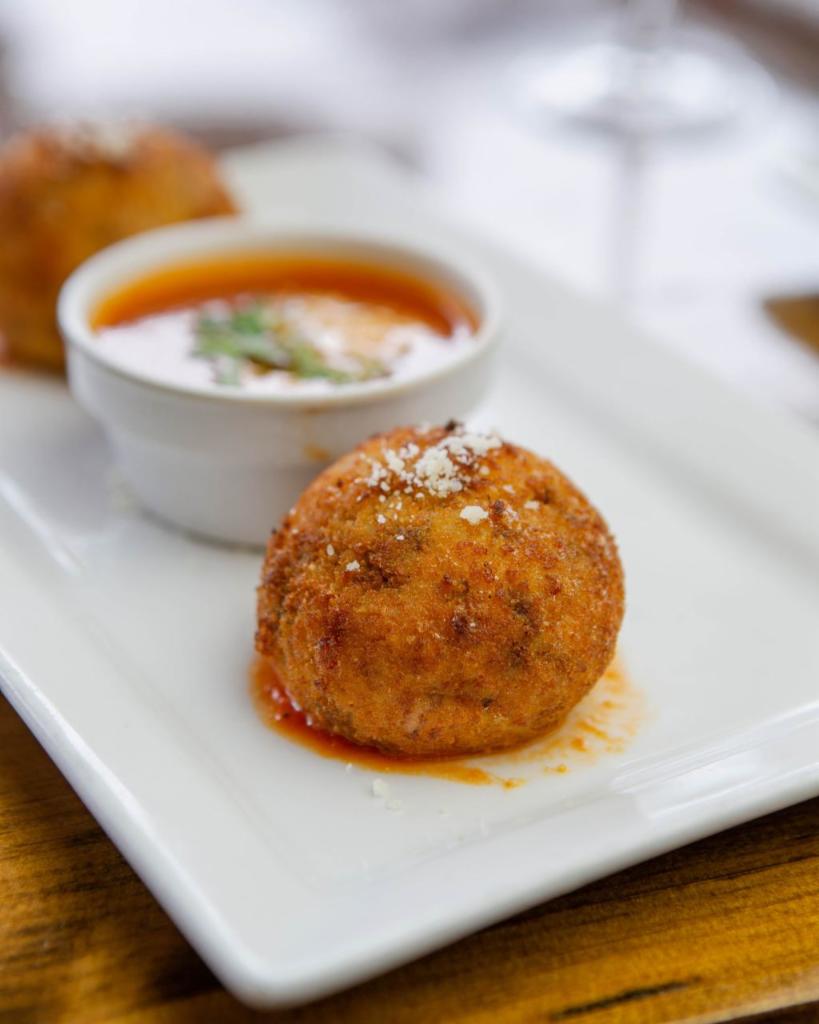 Arancini · Fried rice ball filled with ground beef and shredded mozzarella. Served with a side of tomato sauce.