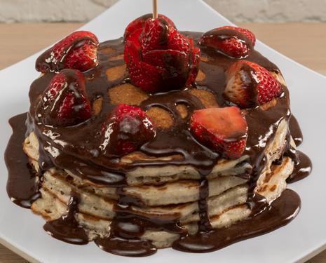 Chocolate Dipped Pancakes · Multi grain protein pancakes with dark chocolate chips topped with strawberries and chocolate protein glaze.