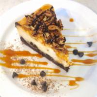 Slice of Turtle Cheesecake · Chocolate cookie crust, vanilla cheesecake, caramel, chocolate ganache & toasted pecans
*con...