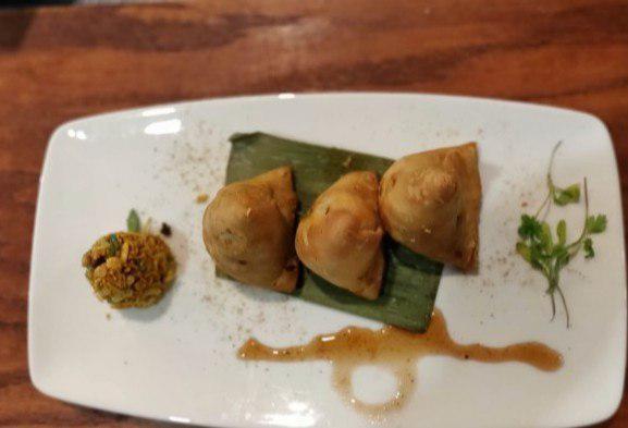 Adraki Samosa · Triangular turnovers filled with potatoes and green peas, a hint of mango powder and flavored with ginger and cumin. Served with mint and tamarind chutney. Vegetarian.