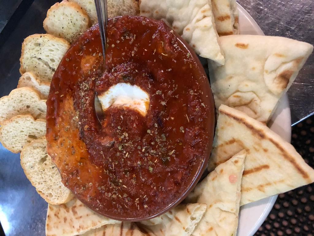 Baked Goat Cheese · Baked goat cheese with tomato basil sauce oven baked in a clay bowl.