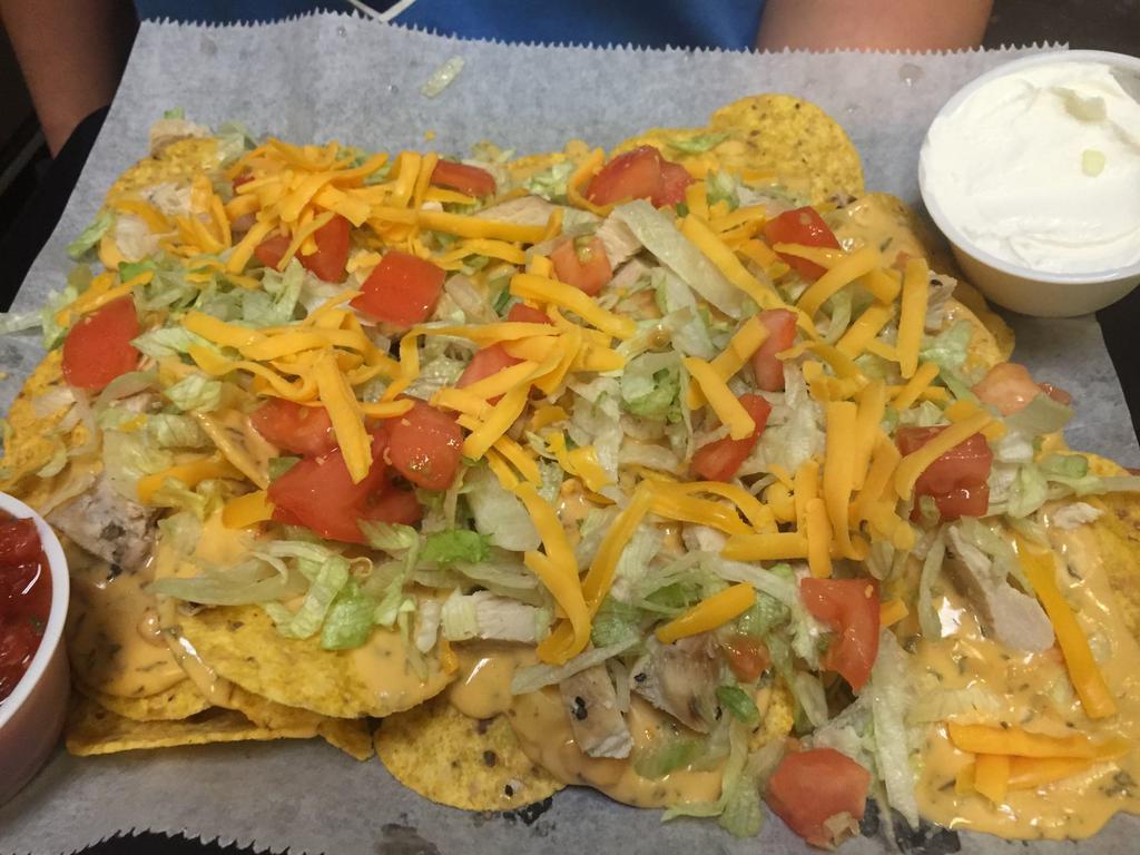Chicken Cheese Nachos · Scattered tortilla chips covered with chili con queso and marinated diced chicken breast. Garnished with lettuce, tomatoes and shredded cheddar cheese. Served with a side of sour cream and salsa.