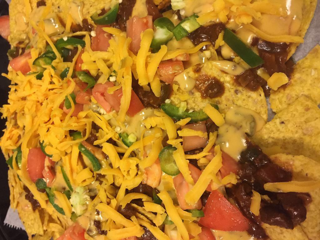 Chili Cheese Nachos · Scattered tortilla chips smothered with our house chili, covered with chili con queso then topped with tomatoes, shredded cheddar and fresh jalapenos.