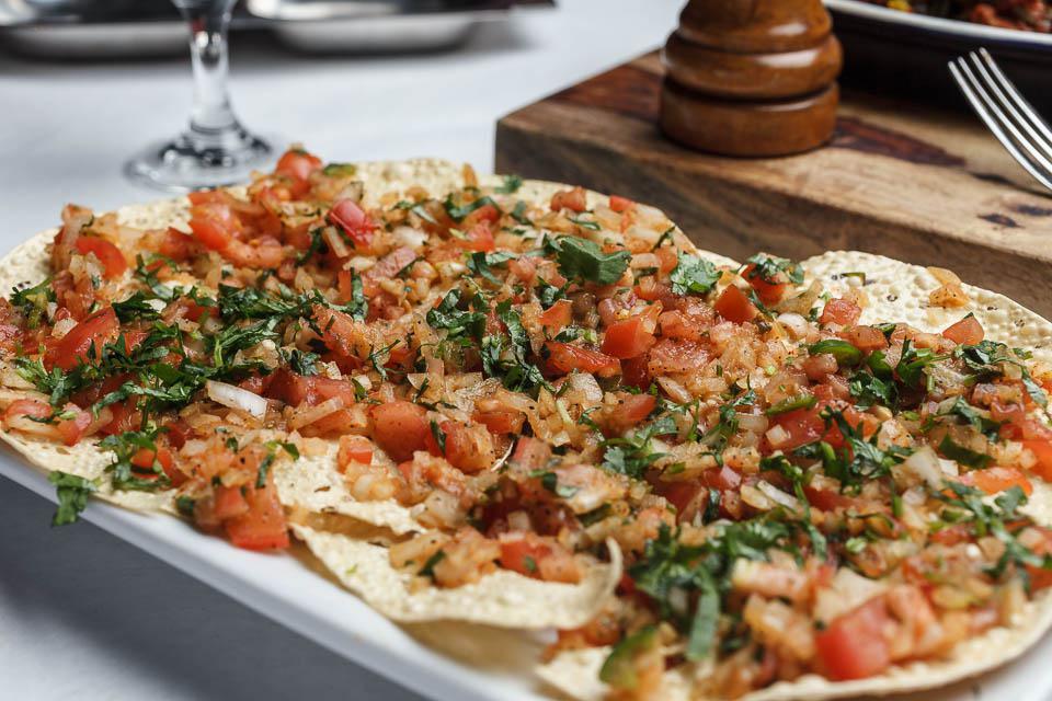 Masala Papad · Traditional Indian lentil chips seasoned with chef's spices and garnished with onion, tomato and cilantro.