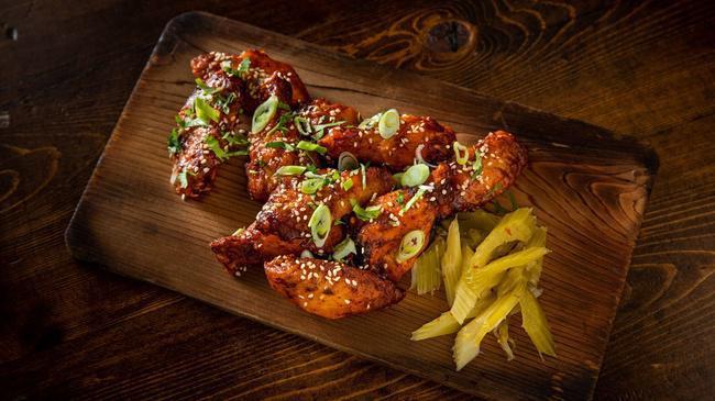 Spicy Wings · Slow-smoked for 2 hours before being flash-fried and tossed in our house-made Chile-Lime Sauce. Topped with toasted sesame seeds, scallion, and fresh cilantro. Served with celery.