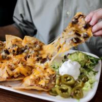Nachos · Refried beans, melted cheddar, and Monterey cheeses. Served with guacamole, sour cream, and ...