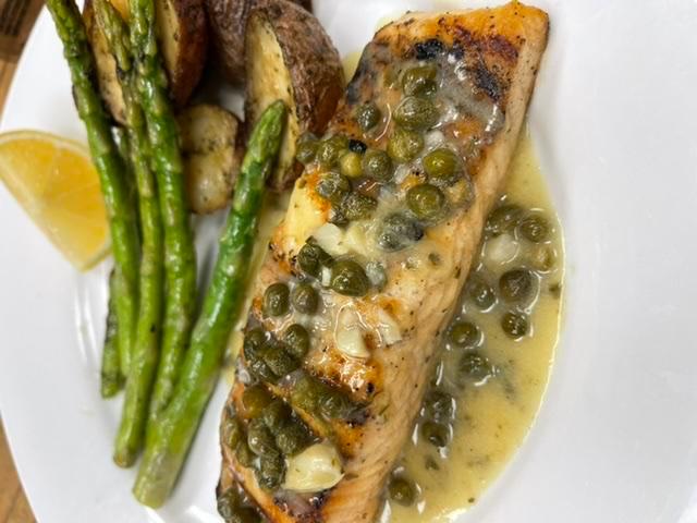 Salmone Piccata · Grilled filet of salmon topped with a lemon-caper butter sauce served with roasted Yukon Gold potatoes & grilled asparagus
