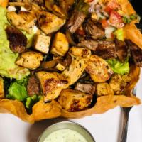 Taco Salad · Fried tortilla bowl filled with romaine lettuce, jack and cheddar cheese, grilled onions, bl...