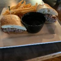 Prime Rib Dip Sandwich · Sliced Prime rib piled high on a fresh baguette bun. Served with au jus for dipping and fries.