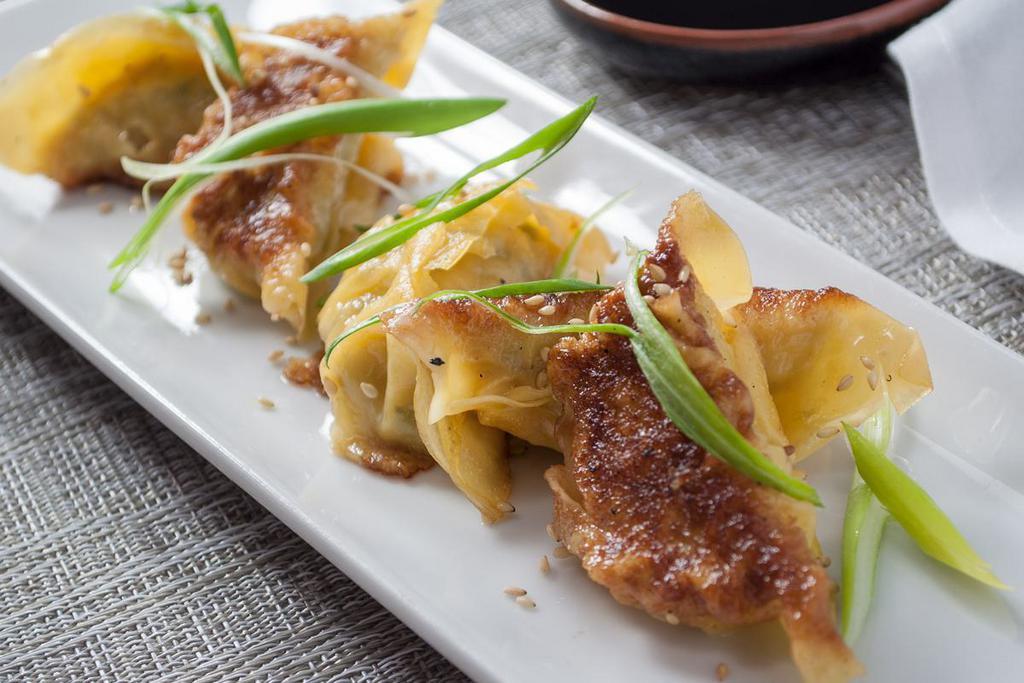 Chicken Gyoza · Ginger and soy chicken dumpling, scallion, sesame seeds and dumpling sauce.

