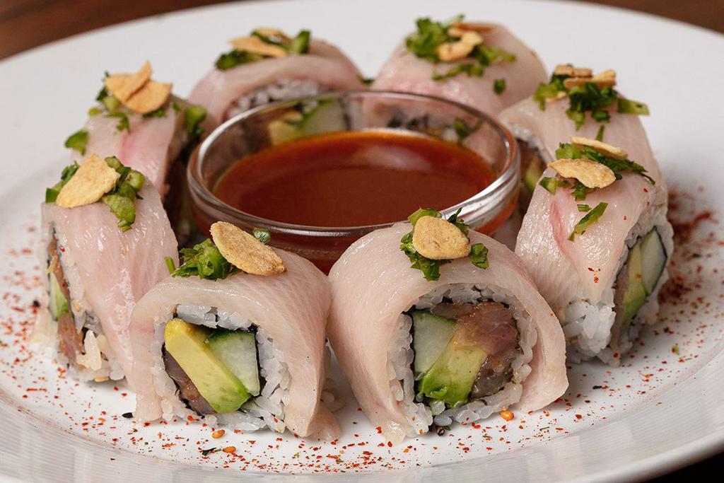 Chili Ponzu Yellowtail Roll · Spicy yellowtail mix rolled with cucumber, avocado, jalapeños and cilantro; topped with yellowtail, green onions, crispy garlic and togarashi; served with chili ponzu sauce
