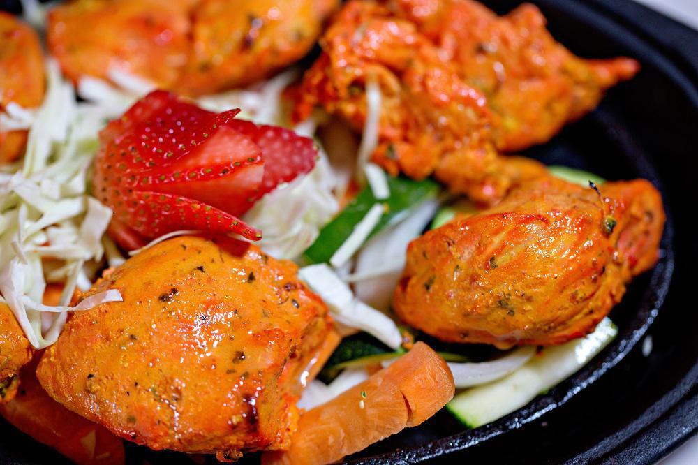 Chicken Tikka · Gluten-free. Marinated boneless chicken breast cubes. Tandoor is a clay oven, marinated freshly baked to order served on a sizzler with fresh cut veggies, low-fat herb yogurt or tikka masala sauce on the side. Served with choice of rice.
