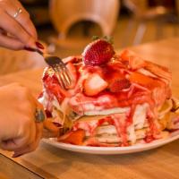 Strawberries and Cream Pancakes · Sliced fresh strawberries in a short stack of pancakes topped with sweet cream frosting and ...