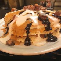 Reese’s Peanut Butter Cup Pancakes · Reese's peanut butter cups sprinkled in a short stack of pancakes topped with warm peanut bu...