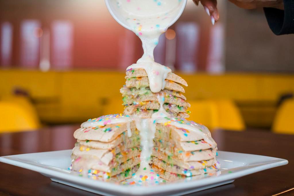 Birthday Cake Pancakes · Birthday quins sprinkled in a short stack of vanilla cake pancakes topped with sweet cream frosting and more fun birthday sprinkles.