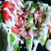 Wedge Salad · Iceberg wedges topped with bacon, blue cheese crumbles, and beefsteak tomatoes finished with...