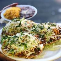 14. Tostadas Fiesta Combinacione · Crispy tortillas topped with shredded chicken, ground beef and guacamole, topped with lettuc...