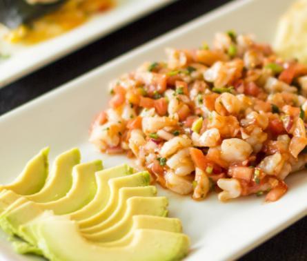 Ceviche Tropical · Prepared in lime juice, mixed with tomatoes, onions and cilantro. Served with sliced avocado and crackers.