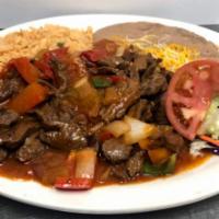 Bistek ranchero  · Grill ranchera meat with bell peppers onions and ranchera sauce . Served with rice , beans a...
