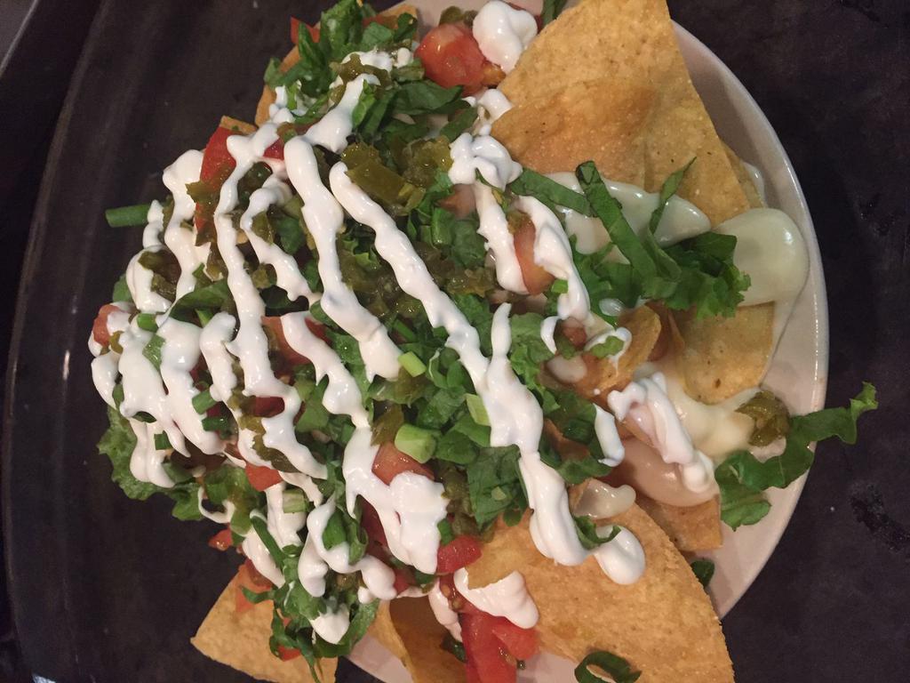 Kick Azz Nachos · Fried tortilla chips, homemade queso cheese, jalapenos, fresh cut lettuce, chopped tomatoes and green onions with sour cream.