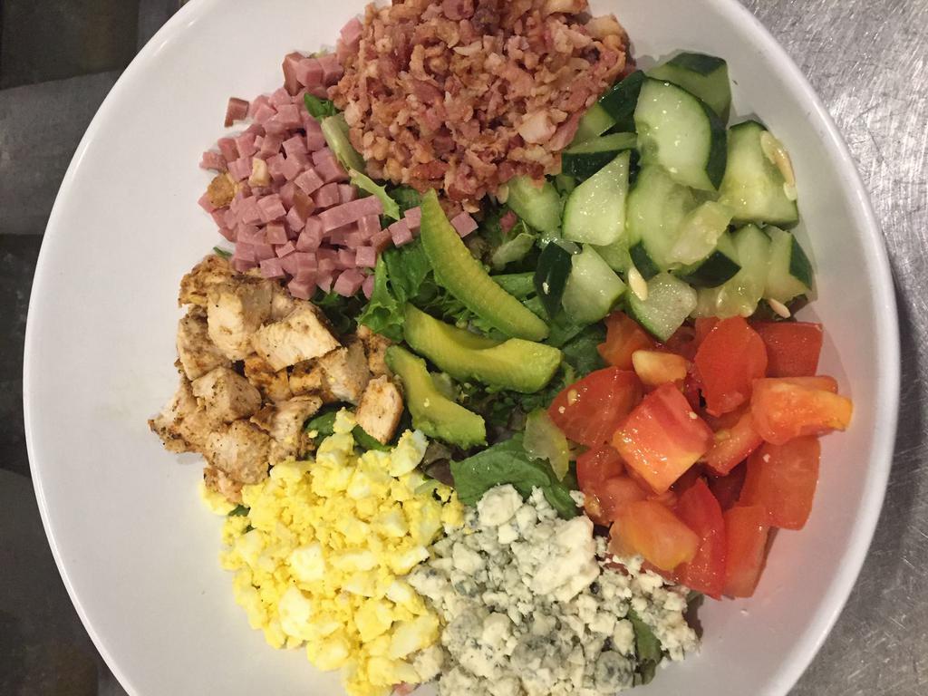 Classic Cobb Salad · Ham, grilled chicken, bacon, sliced avocado, egg slices and bleu cheese crumbles layered over a bed of greens with tomato and cucumber.