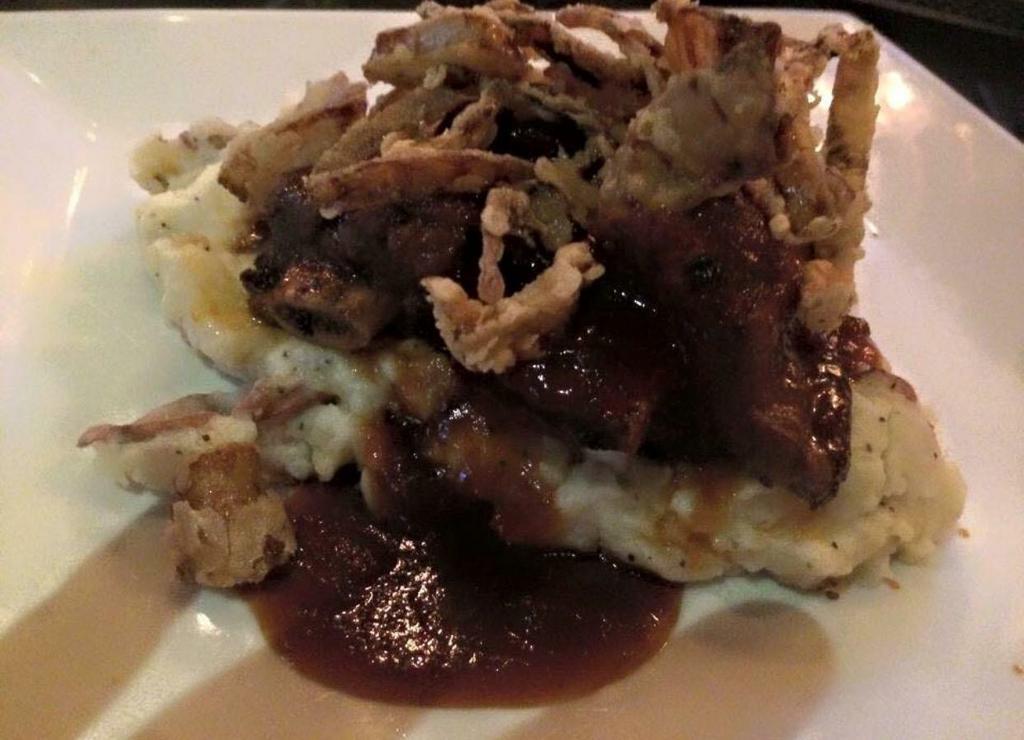 Slow Cooked Beef Short Ribs · Tender slow cooked short ribs served over mashed red skin potatoes. Topped with fried shallot petals and finished with J.D. BBQ glaze.