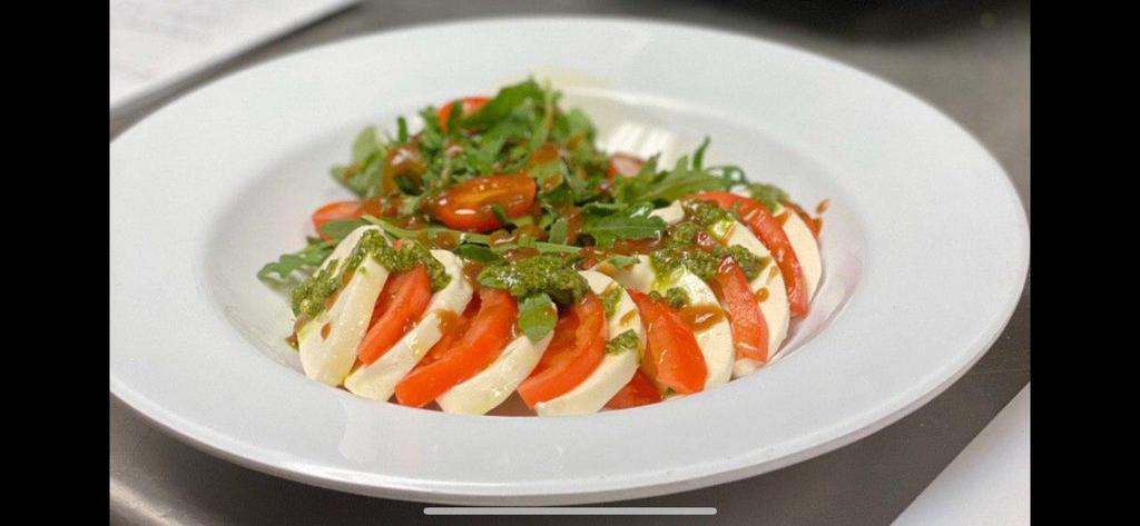 Arugula Caprese Salad · Arugula, fresh mozzarella, cherry tomatoes, pesto sauce with balsamic vinaigrette dressing.