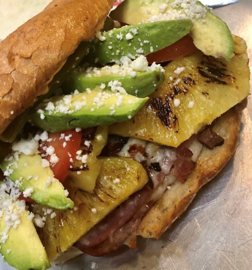 La Hawaiiana Torta · Forest ham and pineapple. Served in a baked telera bread lightly spread with refried beans, housemade smoked chipotle aioli spread, onions, tomatoes, avocado, sour cream and cheese.