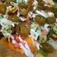 Ultimate Nachos · Crisp tortilla chips loaded with melted cheddar cheese, lettuce, tomatoes, sour cream and to...