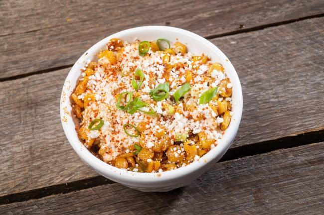Small Street Corn · Grilled corn off-the-cob jacked up with red onion, jalapenos, scallions, chipotle ranch and topped with cotija cheese and dirty rub.