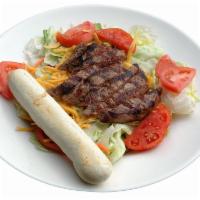 Steak Over Salad · Strips of sizzling steak on top of fresh greens, shredded cheddar Jack, tomatoes and fresh b...