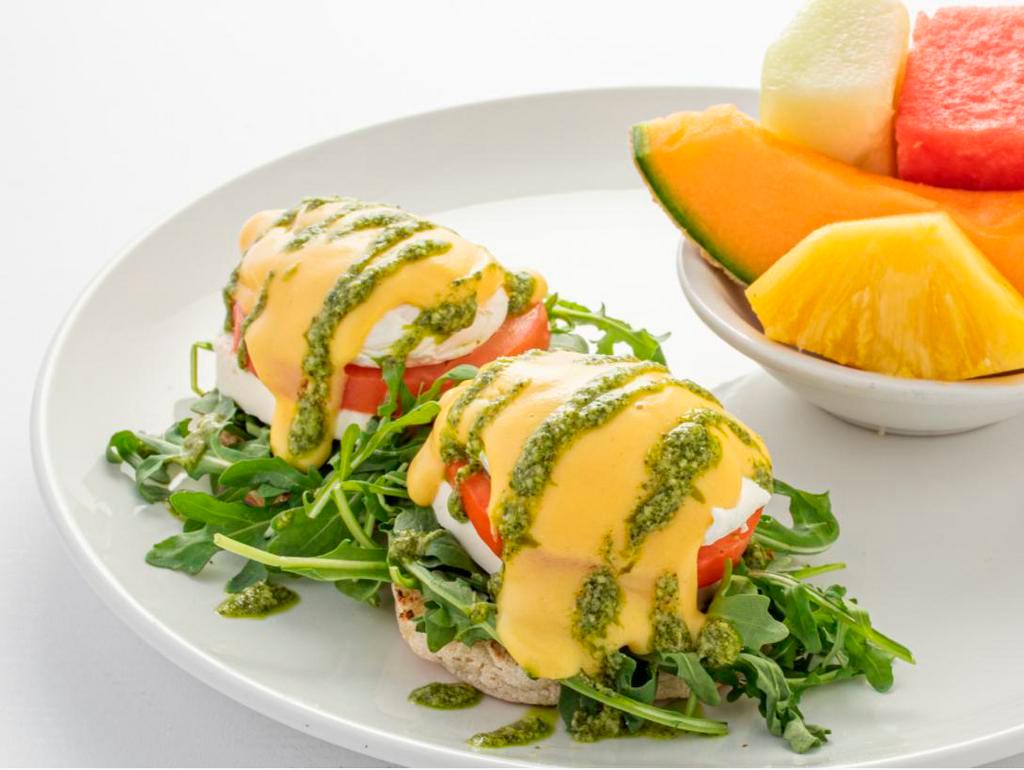 Caprese Benedict · A toasted English muffin topped with arugula, fresh mozzarella cheese, sliced tomato, poached eggs, hollandaise sauce and pesto basil drizzle.
