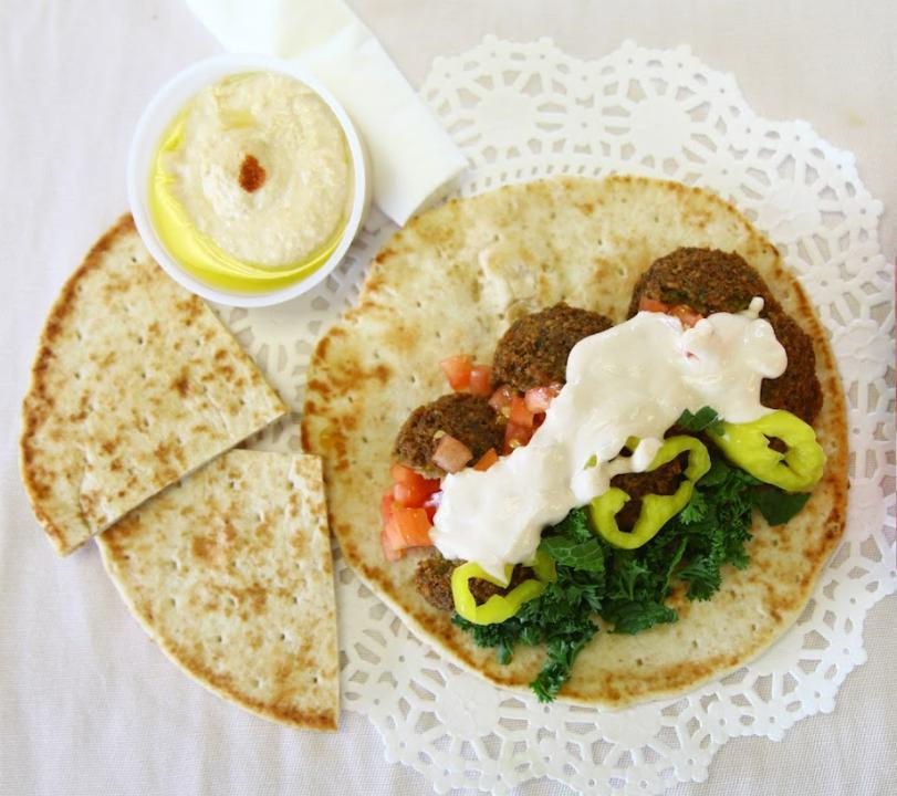 8. Falafel Sandwich Combo · Tomato, lettuce, mint, pickle and our sauce. Wrapped in pita bread. Served with side hummus, half pita bread and a beverage.