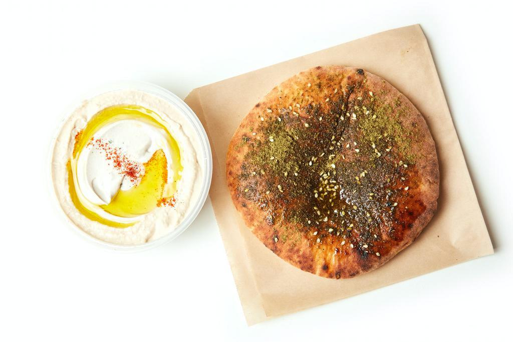 Hummus + Za’atar Pita · Creamy and smooth classic chickpea spread pureed with tahini, lemon, garlic, and cumin. Served with a freshly baked za’atar pita.  Pint includes 2 pitas and a quart comes with 4 pitas.