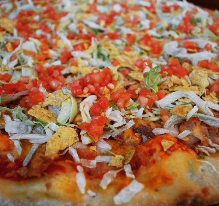Taco Pie · If you’re craving something taco, then order right now! Your taco pizza comes with a taco meat, crushed tortilla chips, shredded colby cheese, tomatoes, lettuce, and our signature red grinder sauce. Don’t let this one slip on by. Choice of taco meat or shredded chicken. Add sour cream for an aditional charge.