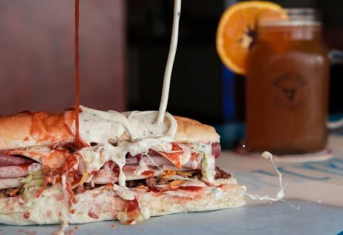 Ultimate Grinder · Turkey, ham, salami, taco meat, Colby cheese, Swiss-American cheese, lettuce, and red and white grinder sauce on top of freshly made bread.