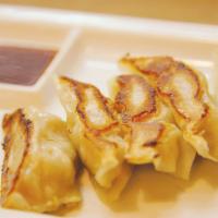 Pork Gyoza · Pan-seared dumplings with a crusted top. Served with sauce.