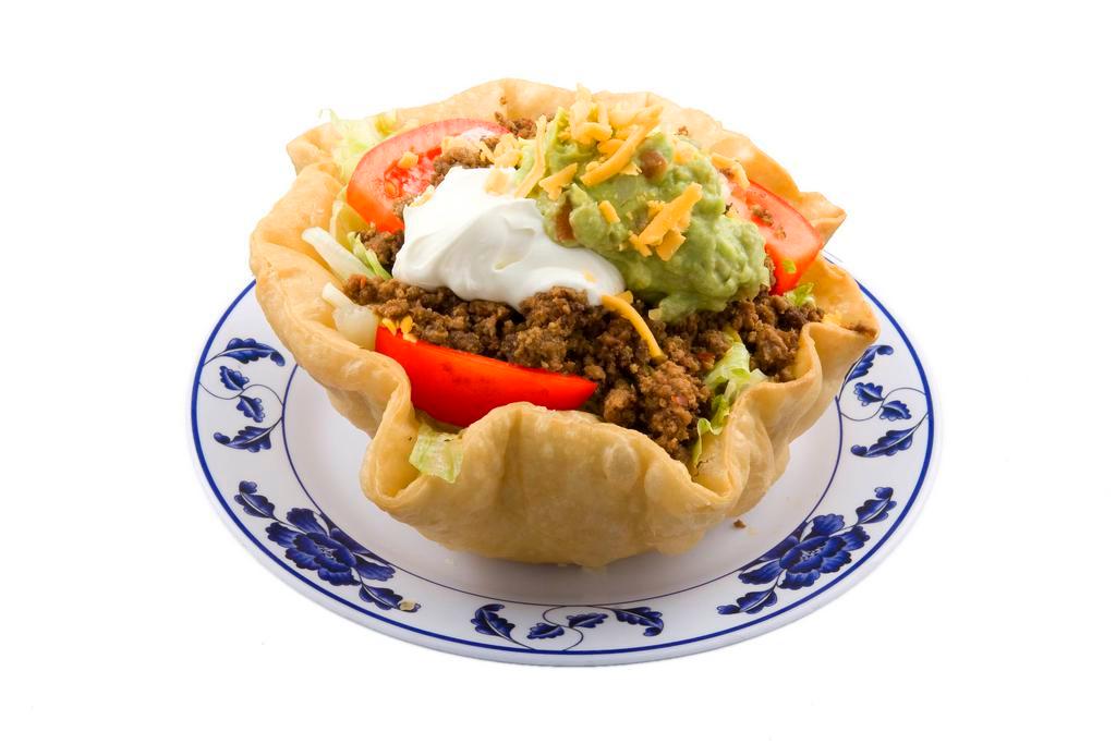 Taco Salad · Crispy flour tortilla bowl filled with beans, lettuce, tomato, cheese, sour cream, guacamole, and choice of meat.