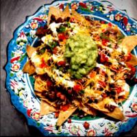 Macho Nachos · Homemade beans over hot fresh chips.  Then we spread creamy nacho cheese, and top them off w...