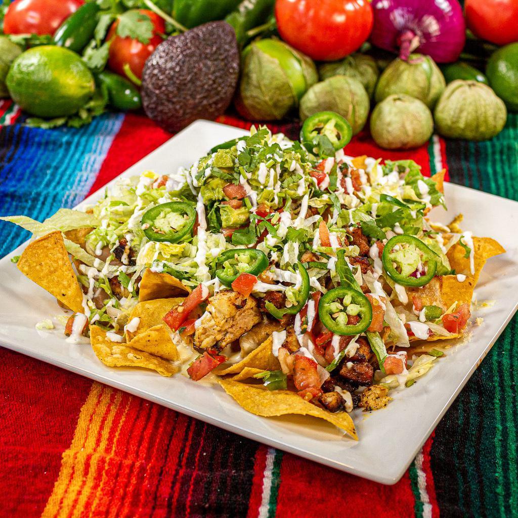 Nachos  · Homemade chips, refried beans, shredded cheese, cheese sauce, lettuce, guacamole, pico de gallo, scallions, jalapeños & sour cream; add shredded chicken, grilled chicken, picadillo (ground beef), or steak.
