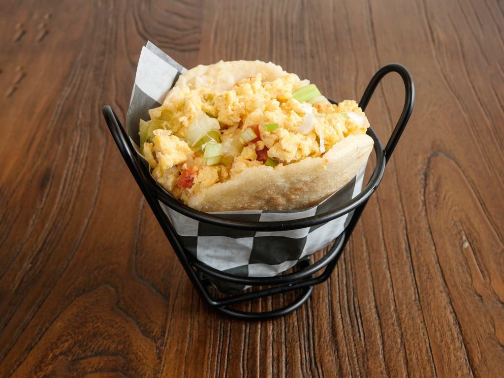 Perico Arepa (V) · Grilled corn dough patty (arepa) filled with scrambled eggs, sautéed diced onions, scallions, and tomatoes.