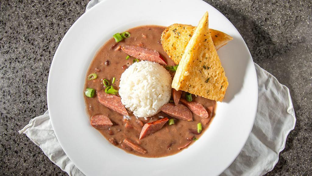 Red Beans ＆ Rice · Simmered red beans and smoked Andouille sausage served on a bed of your choice of white or dirty rice. Garnished with green onion and grilled Andouille sausage.