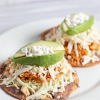 Tostadas con Tinga · Crisp corn tortillas topped with refried beans, shredded chicken in a chipotle sauce, shredd...