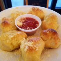 Garlic Knots · Hand knotted dough, baked fresh daily. Topped with a buttery blend garlic & Parmesan cheese