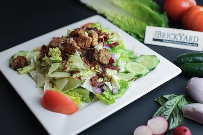 Side House Salad. · romaine, iceberg, cucumber, red onion, tomato, croutons, bacon & chopped egg served in a red wine vinaigrette. picture showing a full size salad.